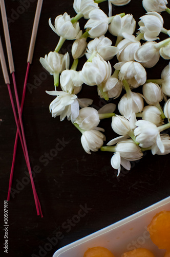 Fragrant jasmine blossom garland wrapped in circle on wooden table traditionally used as an offering to the ghosts and spirits in Thailand.