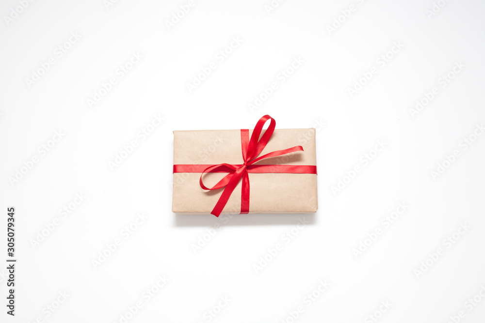 Gift isolated on a white background, Packed in brown paper and decorated with a red ribbon with a bow, there is a place for the inscription. The concept of surprises and gifts.