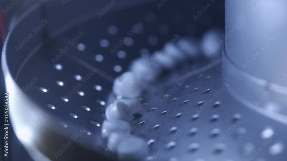 Process of production of pills, tablets. Industrial pharmaceutical concept. Factory equipment and machine. Many pills move on the machine. Medical capsules are sorted by a conveyor belt. Process of production of pills, tablets. Industrial pharmaceutical concept. Factory equipment and machine. Many pills move on the machine. Medical capsules are sorted by a conveyor belt.