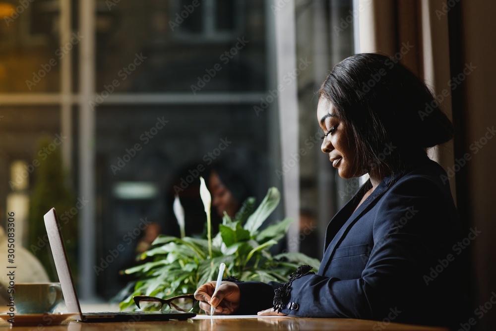 Hard work ensures success. Concentrated young African women working on laptop while sitting at working place Hard work ensures success. Concentrated young African women working on laptop while sitting at working place