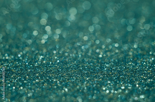 Abstract New Year emerald bokeh background with shining defocus sparkles. Blurred glitters shimmering dust macro close up, copy space for text logo