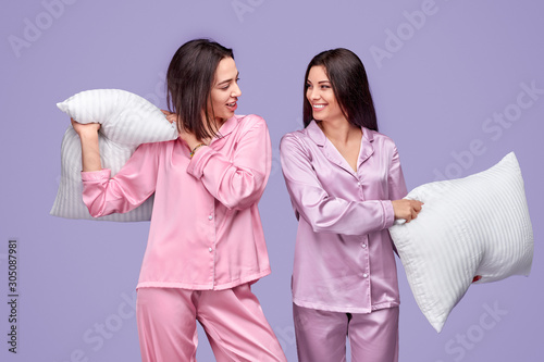 Cheerful women fighting with pillows during sleepover