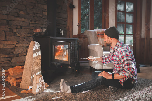 Man in cabin stoking a fire in a woodstove