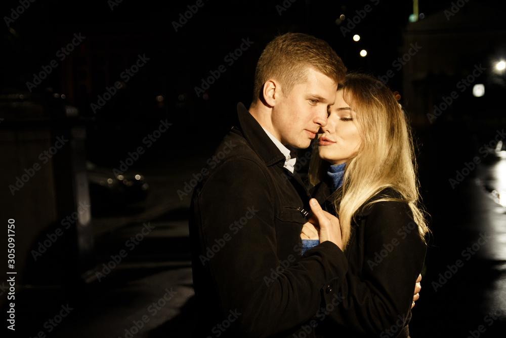 couple in love embracing against a dark background, night, rain, buildings in the city, a park, smiling, attraction. the guy hug the girl. Valentine's Day couple in love embracing against a dark background, night, rain, buildings in the city, a park, smiling, attraction. the guy hug the girl. Valentine's Day