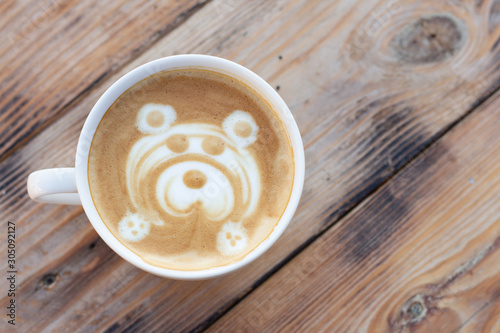 Mug of coffee on a wooden table. Cappuccino with a bear pattern. Top view