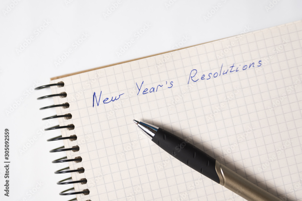 Phrase New Year's resolutions in a notebook, a pen. Close-up Phrase New Year's resolutions in a notebook, a pen. Close-up