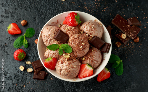 Chocolate Ice Cream with dark chocolate bars, strawberry and hazelnuts in a white bowl