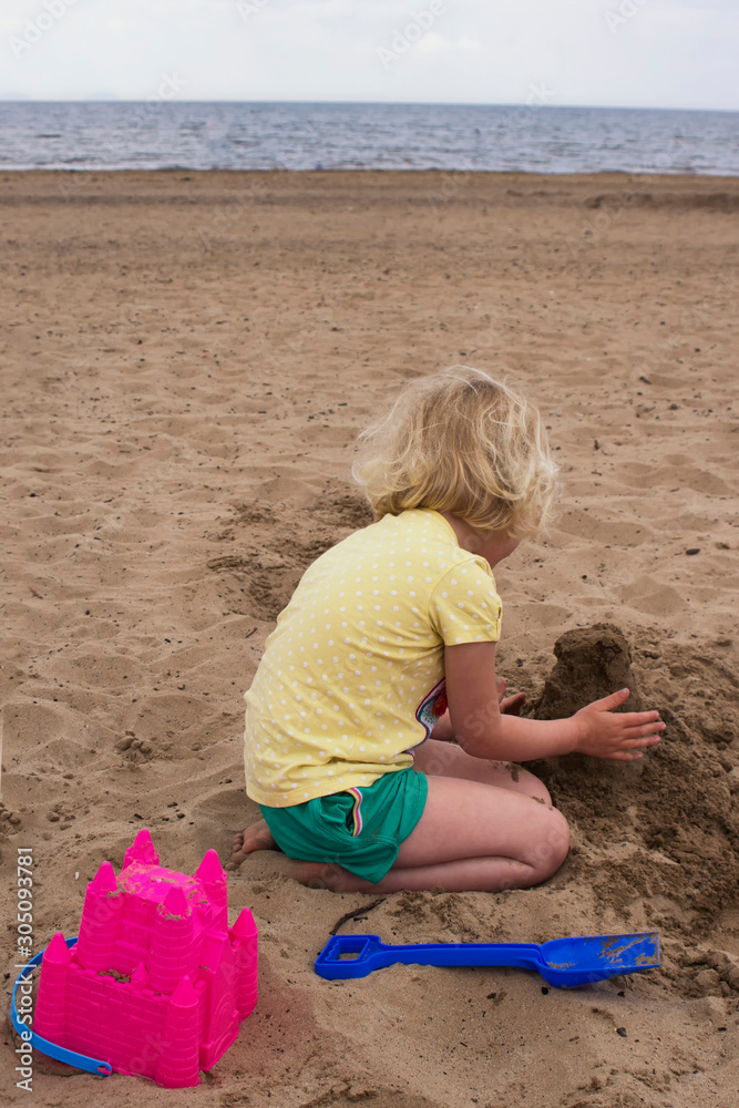 Young girl building a sand castle on a Scottish beach in the summer time Young girl building a sand castle on a Scottish beach in the summer time