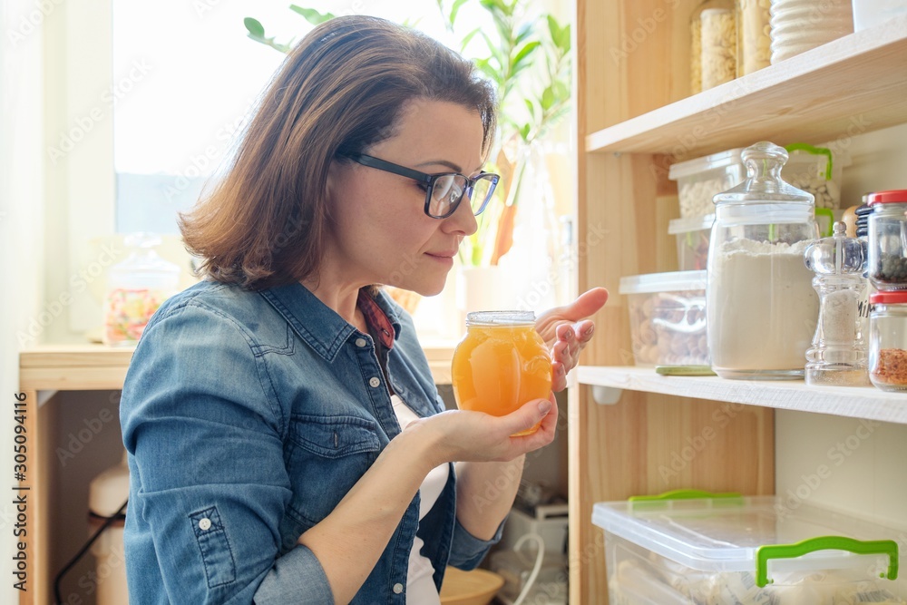 Woman with jar of golden organic fresh honey in the kitchen Woman with jar of golden organic fresh honey in the kitchen