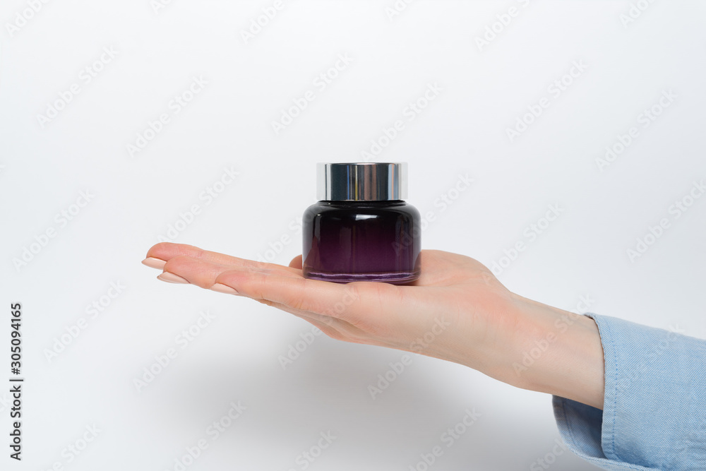 Glass jar for cosmetics in a female hand. White background Glass jar for cosmetics in a female hand. White background