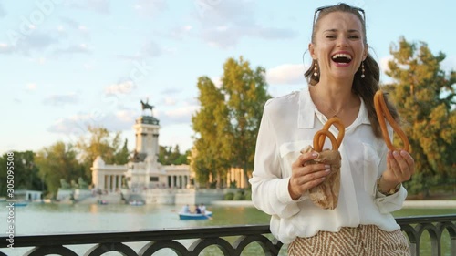 happy modern tourist woman in white blouse and shorts in Madrid, Spain eating traditional Spain churro. churros - classic Madrid sweet snack. woman travel alone. perfect destination choice.solo travel