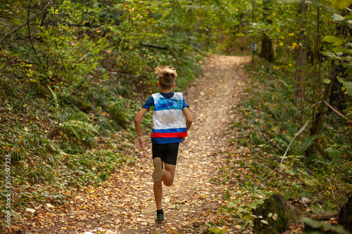Fototapeta Naklejka Na Ścianę i Meble -  Running competition. A child runs through the forest.