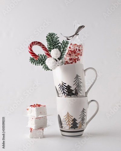 A Christmas sweet gift composition with fir, marshmellow, sweets in a mug on white background. photo