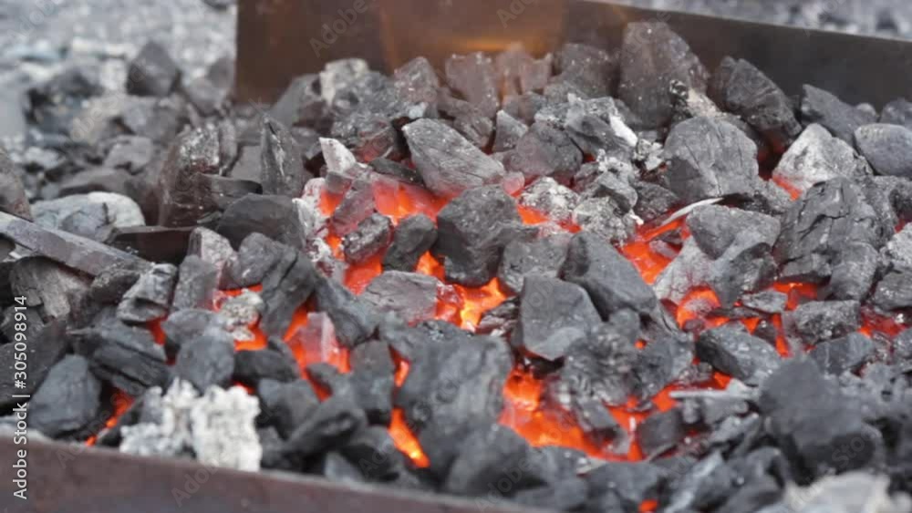 A blacksmith take out by a tongs red-hot bar horseshoe from a blacksmith's brazier. Flame and flying sparks flow of glowing embers. A blacksmith take out by a tongs red-hot bar horseshoe from a blacksmith's brazier. Flame and flying sparks flow of glowing embers.