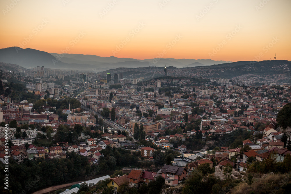 Arial view of a city from a hill during sunset, Sarajevo Bosnia and Herzegovina. The whole city with mountains layers in the background.