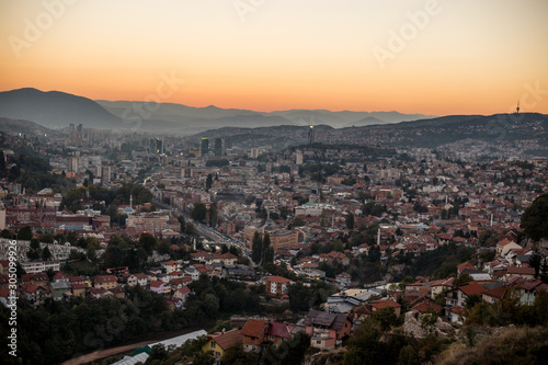 Arial view of a city from a hill during sunset, Sarajevo Bosnia and Herzegovina. The whole city with mountains layers in the background. © Melika