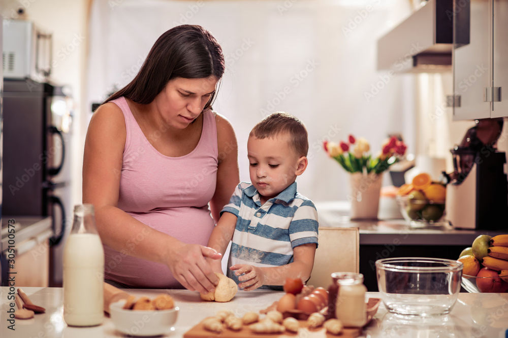 Pregnant woman and son making cookies