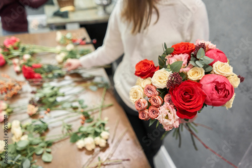 Fototapeta Naklejka Na Ścianę i Meble -  Step by step florist woman creates red beautiful bouquet of mixed flowers. Handsome fresh bunch. Education, master class and floristry courses. Flowers delivery. European floral shop concept.