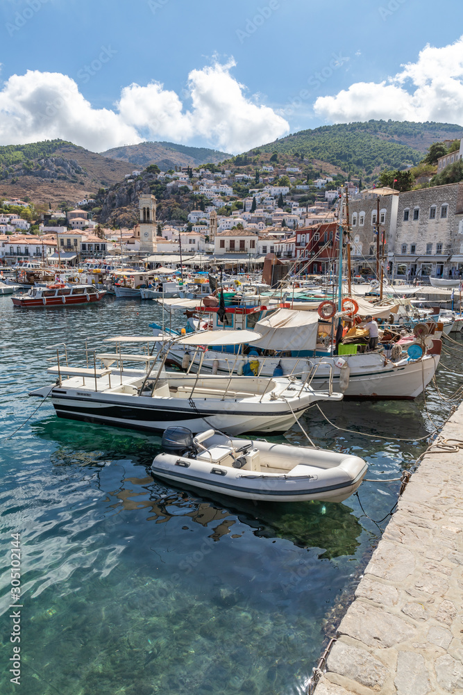 Boats in the pier with houses and buildings in background in Hydra Island