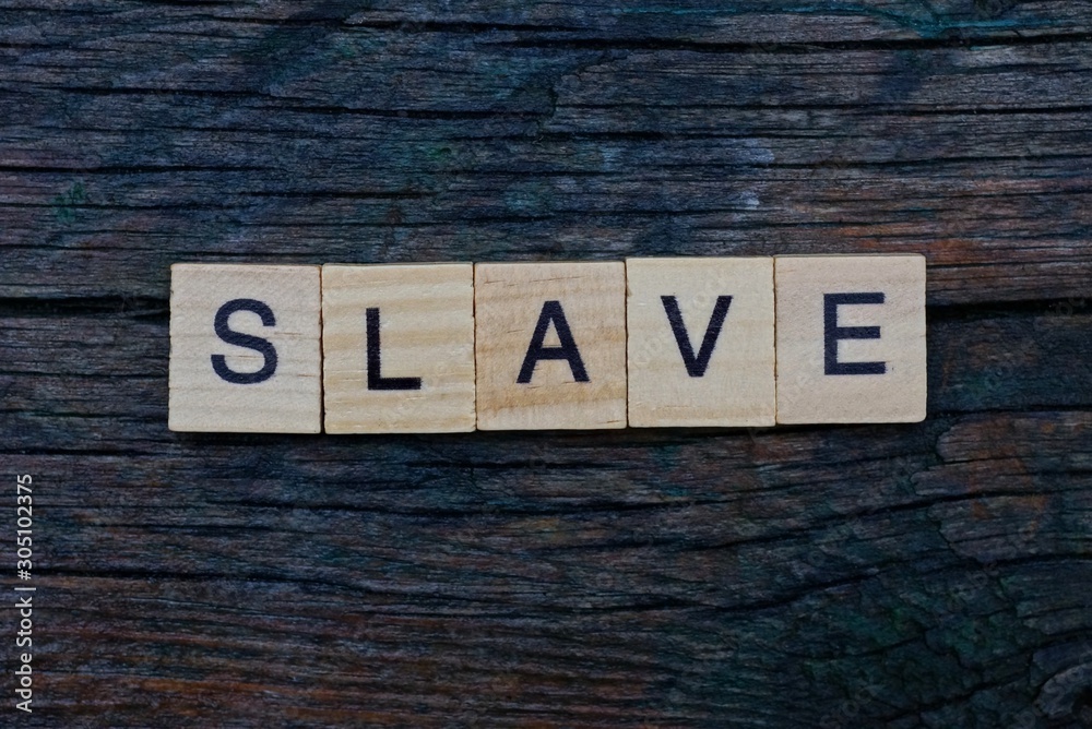 Fototapeta premium word slave made from gray wooden letters lies on a gray table