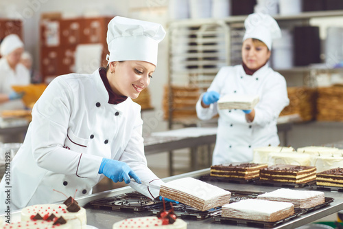 Photos A confectioners squeezes liquid cream from a pastry bag.