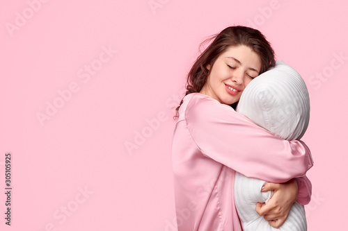 Tender female in sleepwear embracing pillow photo