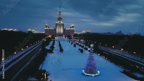 Glowing in the night the main building of Moscow State University (MGU) in the New Year and a luminous by garlands large Christmas tree nearby. Copter ( drone ) shooting
