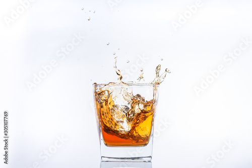 Whiskey and ice. Rum with ice. Brown brandy with splashes. Ice cube falls into a glass w