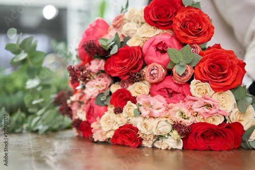 European floral shop concept. Florist woman creates red beautiful bouquet of mixed flowers. Handsome fresh bunch. Education, master class and floristry courses. Flowers delivery.