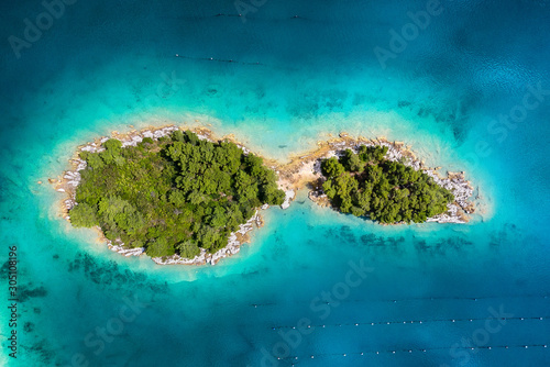 Islands with trees in the middle of the sea. Turquoise water in the Mediterranean Sea. Summer landscape in Croatia from the air.