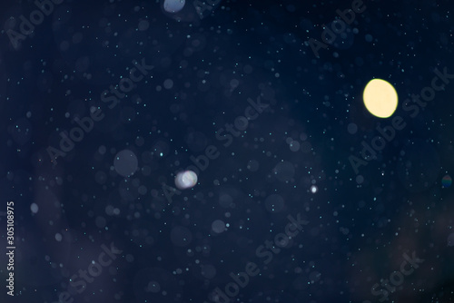 Abstract falling snow or rain bokeh texture overlay on blue background. © Andrii Arkhipov