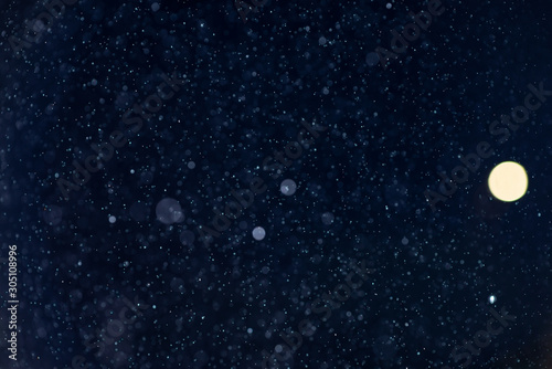 Abstract snow or rain bokeh texture overlay on blue background. © Andrii Arkhipov