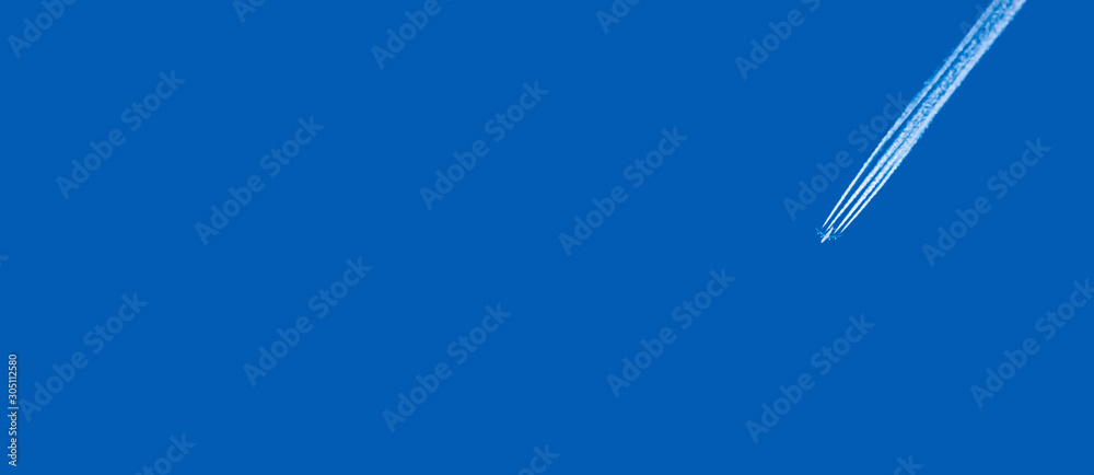 Airplane and white jet trail in clear blue sky. Copy space. Travel by air concept. Tourism advertisement template. Airplane and white jet trail in clear blue sky. Copy space. Travel by air concept. Tourism advertisement template.