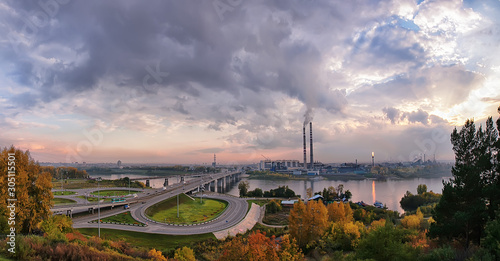 summer cityscape, view of the modern bridge over the river, road junction and overpass. clouds in the sky sunset light, view of factory pipes