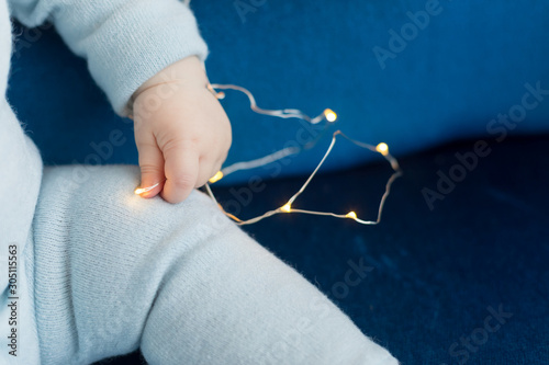 baby's hands. the child is holding a garland . Christmas toy