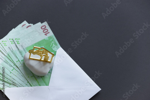 Euro banknotes in white envelope and house figure on black background. Flat lay overhead view. Copy space. Mortgage load concept. photo