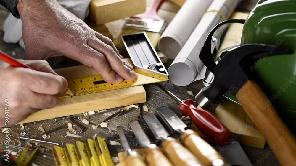 View from above. Carpenter with the pencil and the carpenter's square drawing the cutting line on a wooden board. Construction industry, do it yourself. Wooden work table.