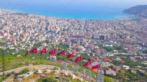 Aerial view of breathtaking coastal city near the blue sea, resort and holidays concept. Clip. Amazing landscape with Turkey flags on the green hill and the summer city. photo