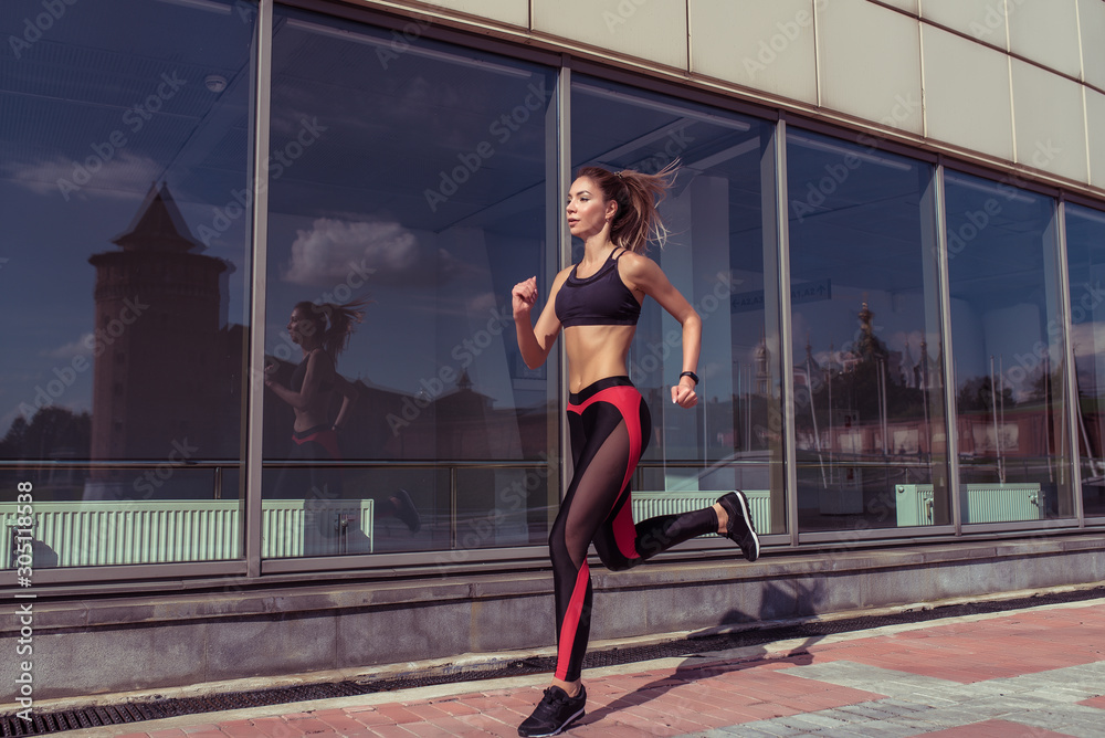 Beautiful dynamic sporty girl runs on jog in morning, lifestyle motivation in summer in city. Sportswear leggings top sneakers, tanned figure. Free space for copy text. Woman motion in jump.
