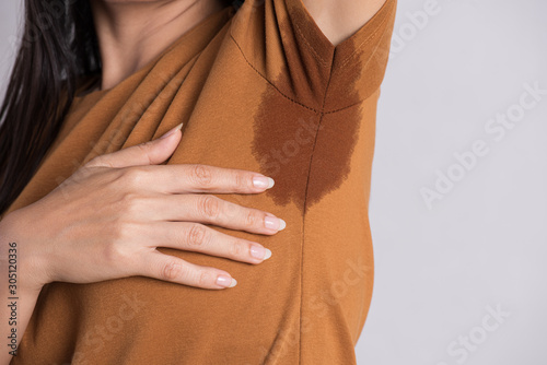 Close-up asian woman with hyperhidrosis sweating. Young asia woman with sweat stain on her clothes against grey background. Healthcare concept. photo