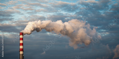 smoke into the sky from a factory chimney against a blue cloudy sky. environmental concept. copy space