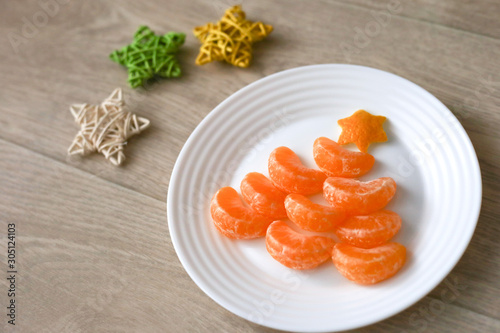 Fruit tangerine Christmas tree on wooden background. New year food background top view. Funny edible Christmas tree. Christmas breacfast idea for kids. Space for text