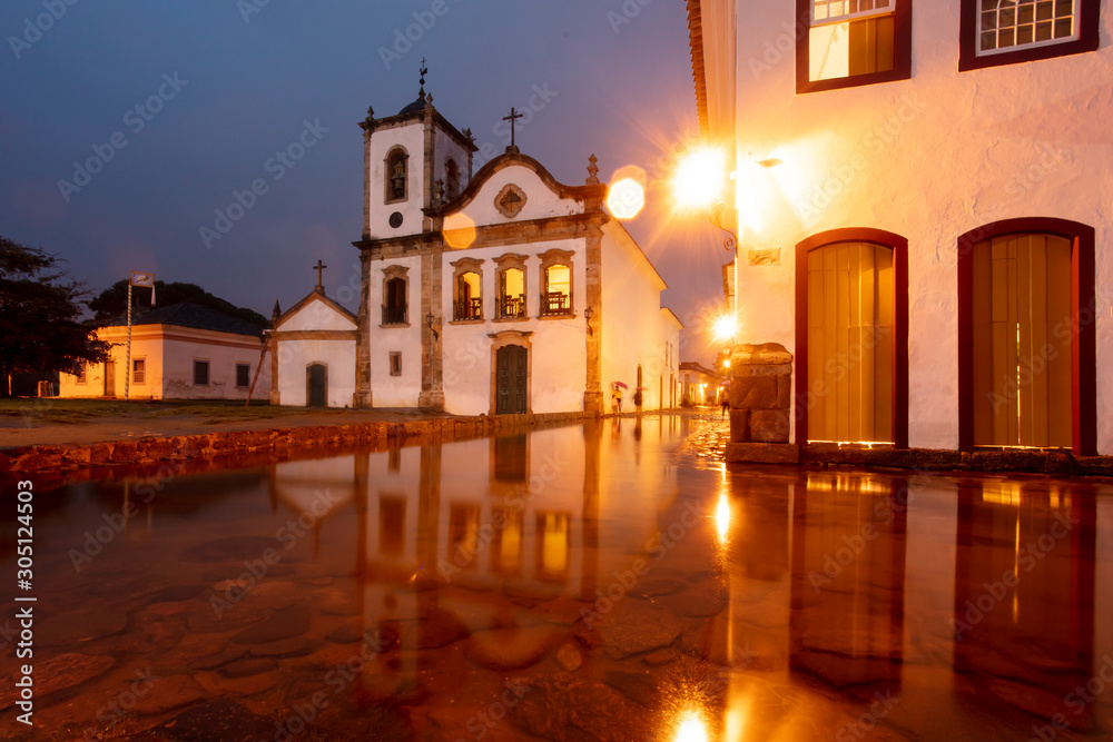 Church in flooded street at night in the historical center of Paraty, Rio de Janeiro, Brazil, World Heritage. Paraty is a preserved Portuguese colonial and Brazilian imperial city.