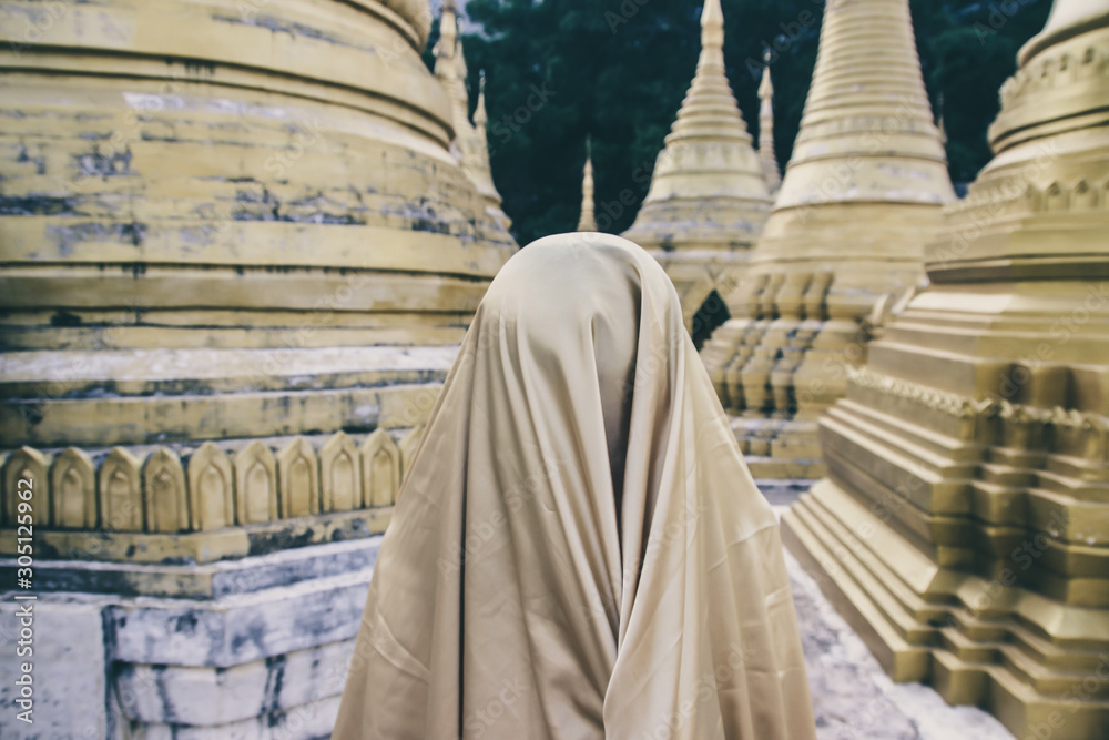 Creature in a gold floaty robe walking along ancient golden Myanmar Buddhist temples and stupas experimental shoot