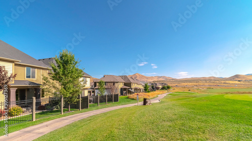 Panorama frame Houses and pathway along a golf course with scenic mountain and blue sky view
