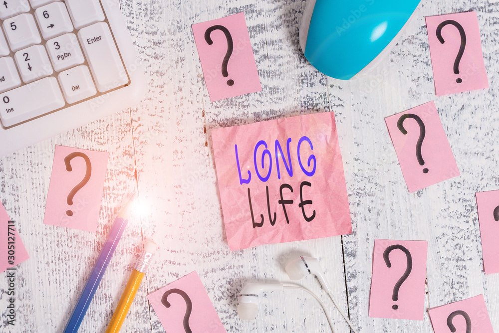 Conceptual hand writing showing Long Life. Concept meaning able to continue working for longer than others of the same kind Writing tools and scribbled paper on top of the wooden table Conceptual hand writing showing Long Life. Concept meaning able to continue working for longer than others of the same kind Writing tools and scribbled paper on top of the wooden table