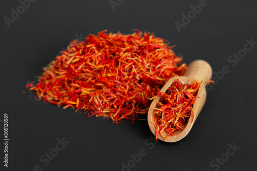 Many spicy saffron spice in the whole background with a wooden spice spatula photo