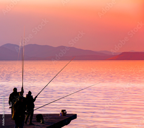 fishermanes silhouette fishing at sunset on the see