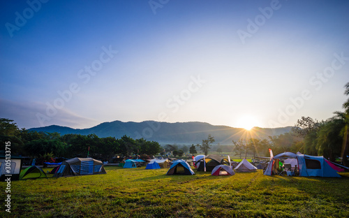 Camping and tent in nature park with sunrise behind the mountain