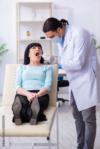 Old woman visiting young doctor dentist